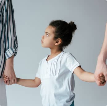 two adults holding angry child's hand